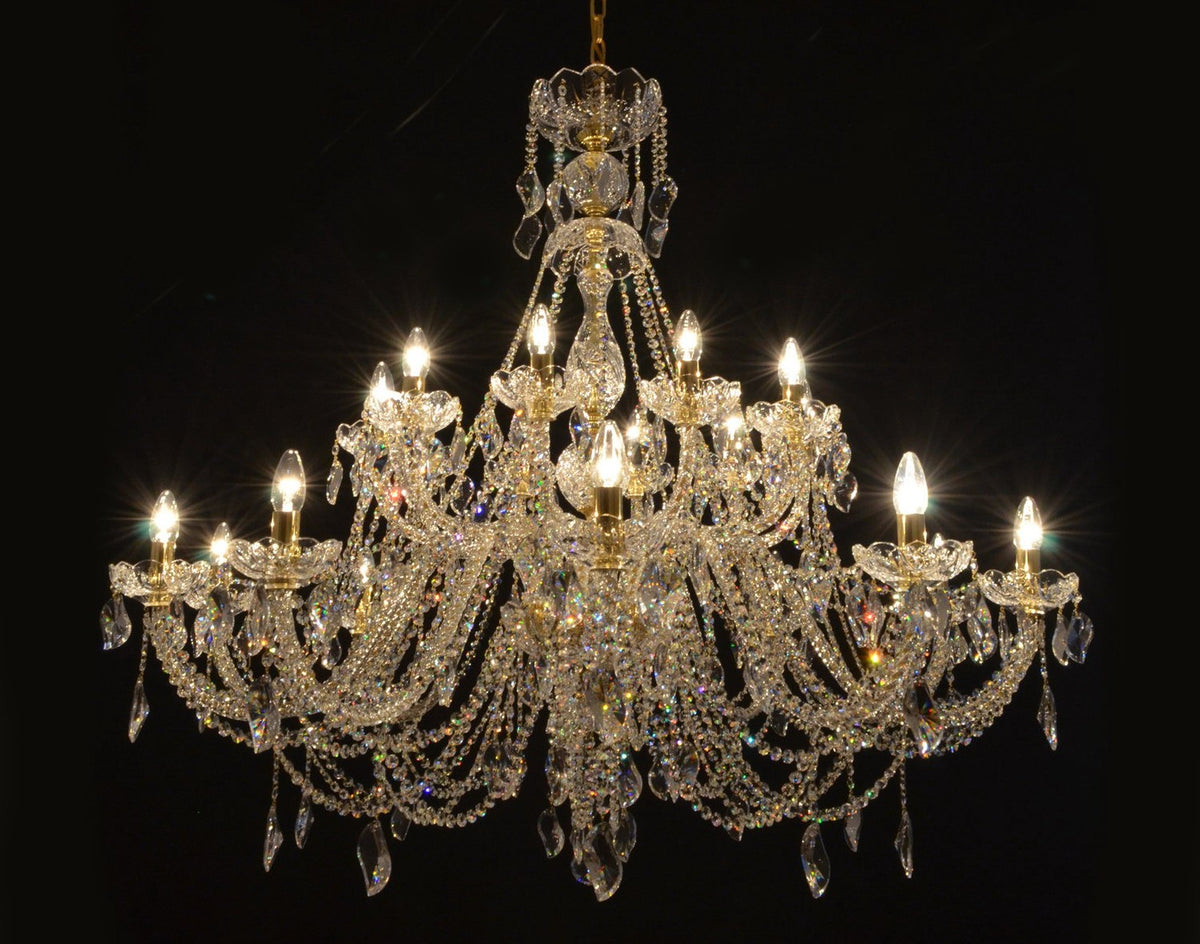 Lustre en cristal allumé, vue de face sur fond noir, dévoilant ses nombreux bras.