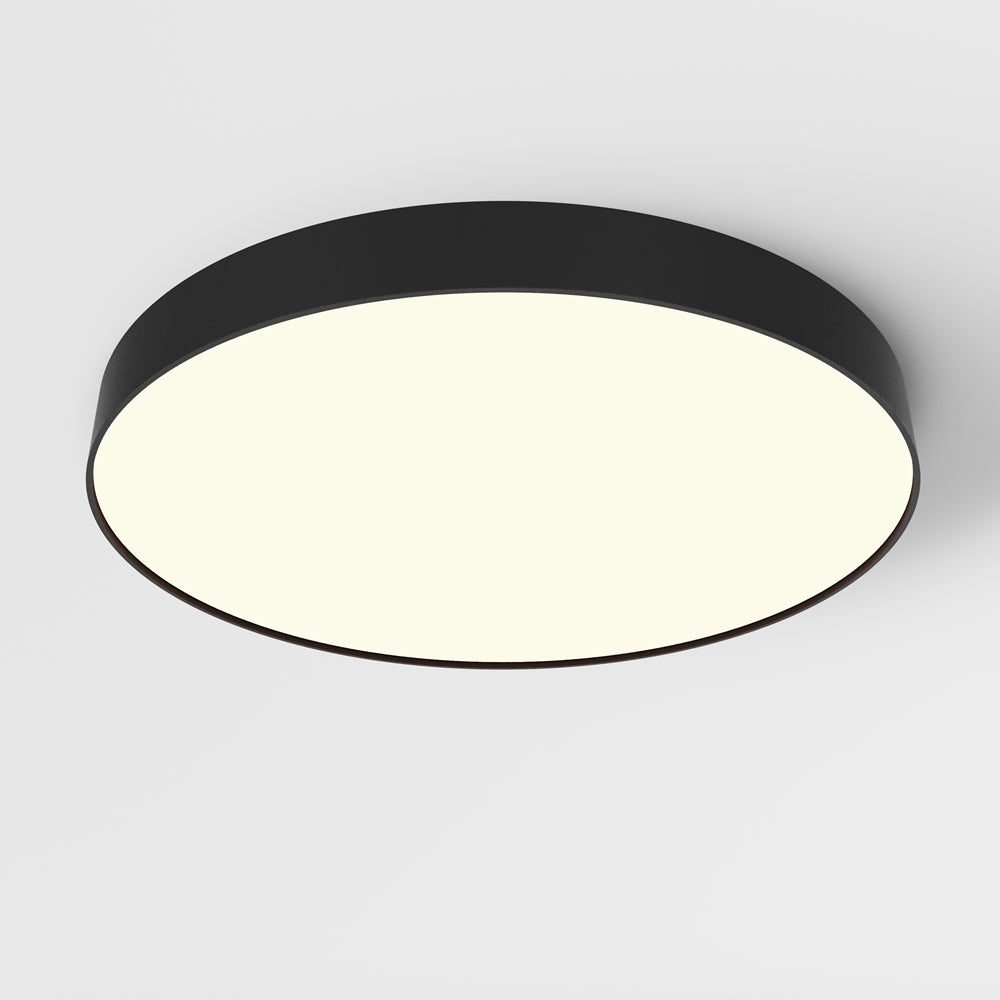 Plafonnier rond noir vu de biais, diffuseur blanc allumé