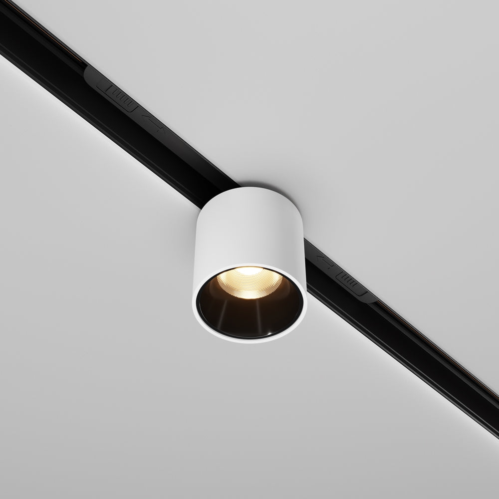 Spot cylindrique blanc fixé sur rail noir, vue de face sous plafond