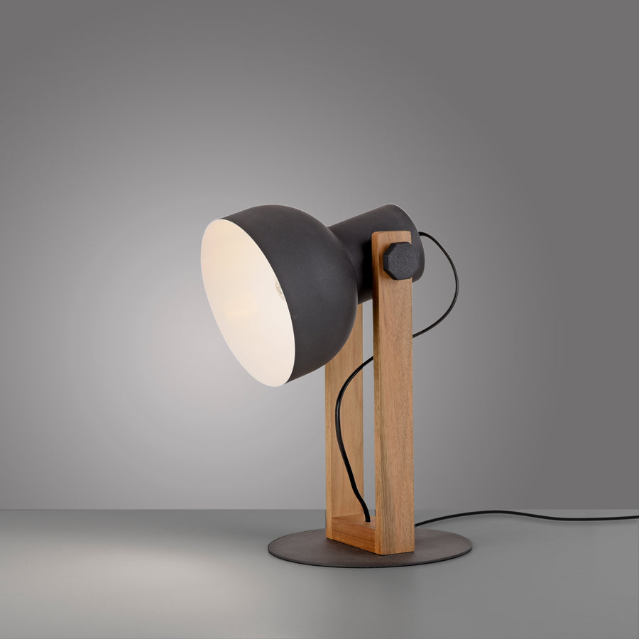 Lampe à poser éclairée sur fond dégradé gris, câble noir visible au sol.