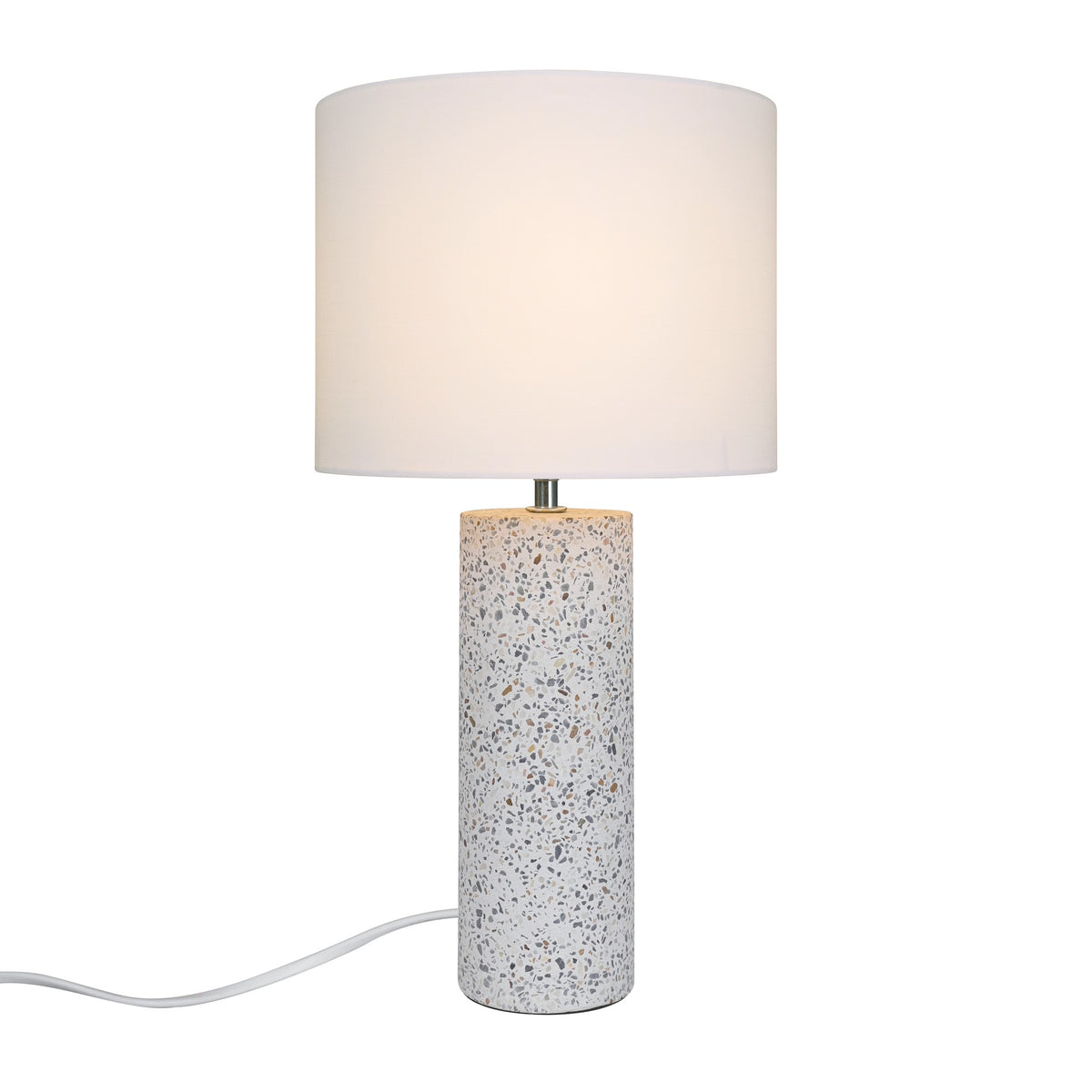 Lampe à poser blanche de face, base cylindrique en terrazzo et abat-jour tissu allumé