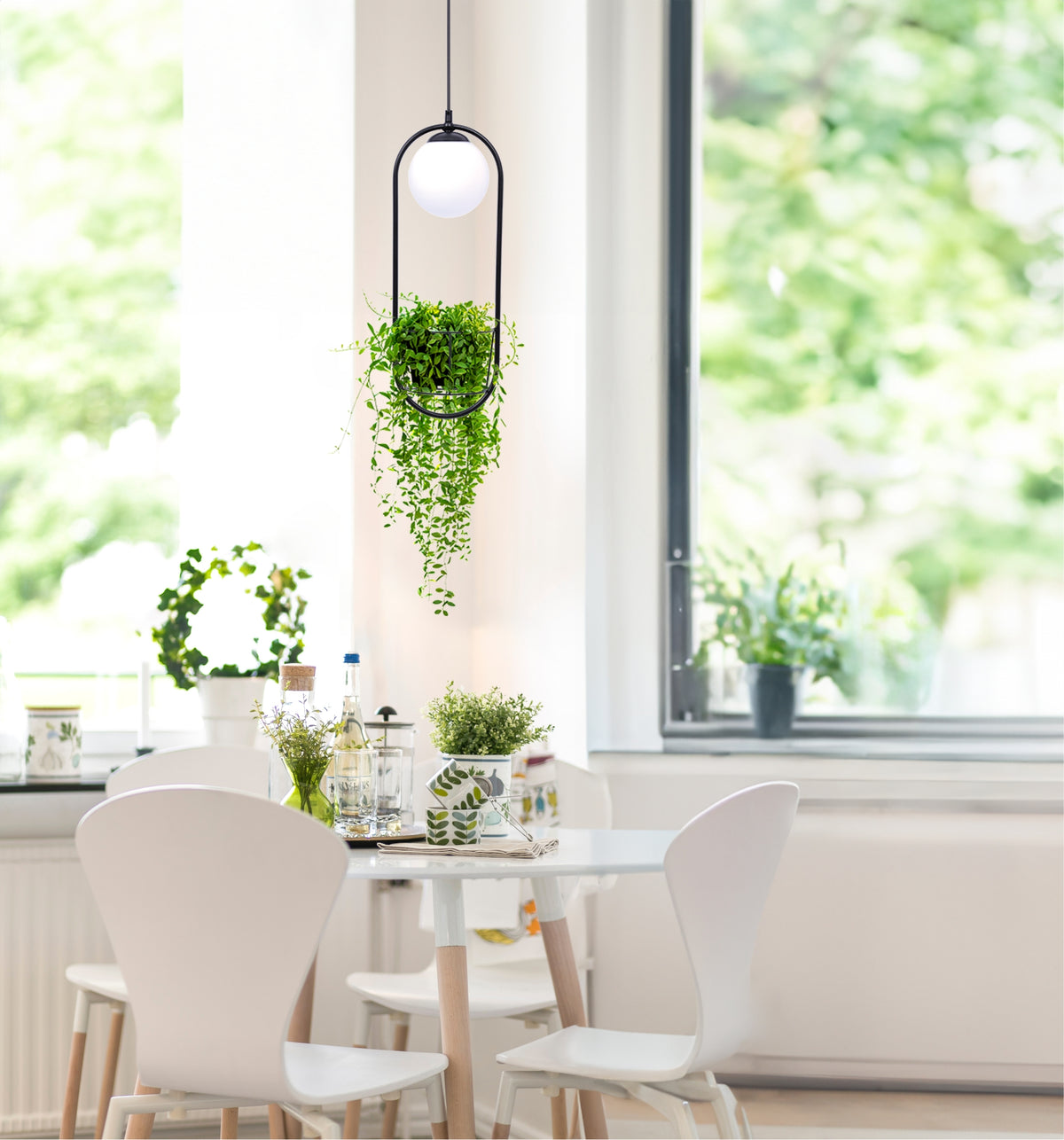 Suspension allumée près d'une fenêtre, intérieur blanc lumineux et plantes.