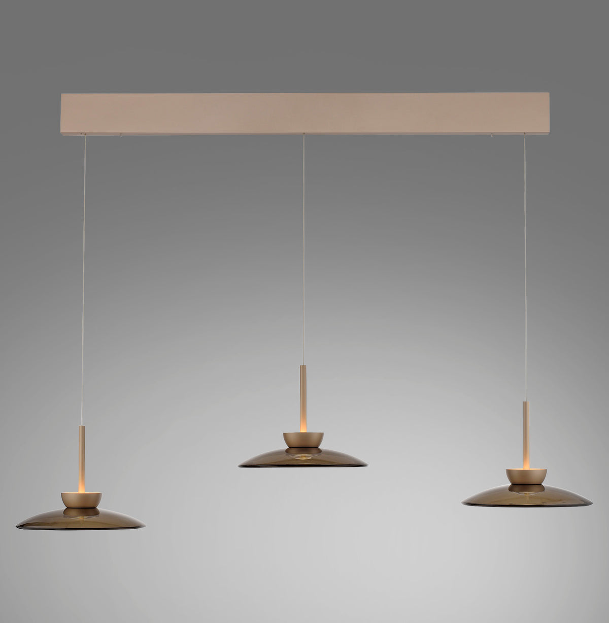 Vue de face du luminaire à trois suspensions en verre ambré sous un rail rectangulaire