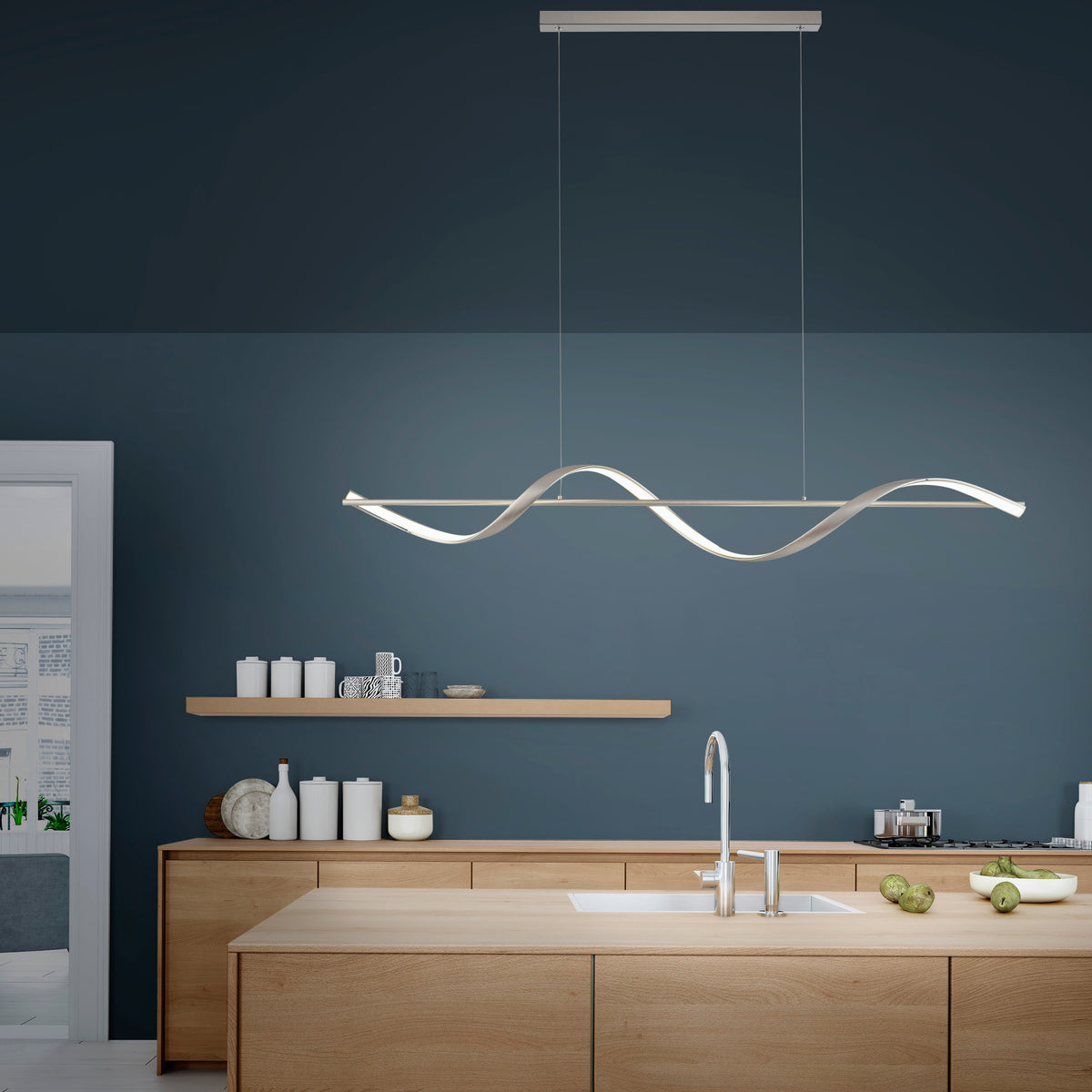 Suspension installée au-dessus d'un îlot de cuisine moderne, mur bleu et meubles en bois clair.