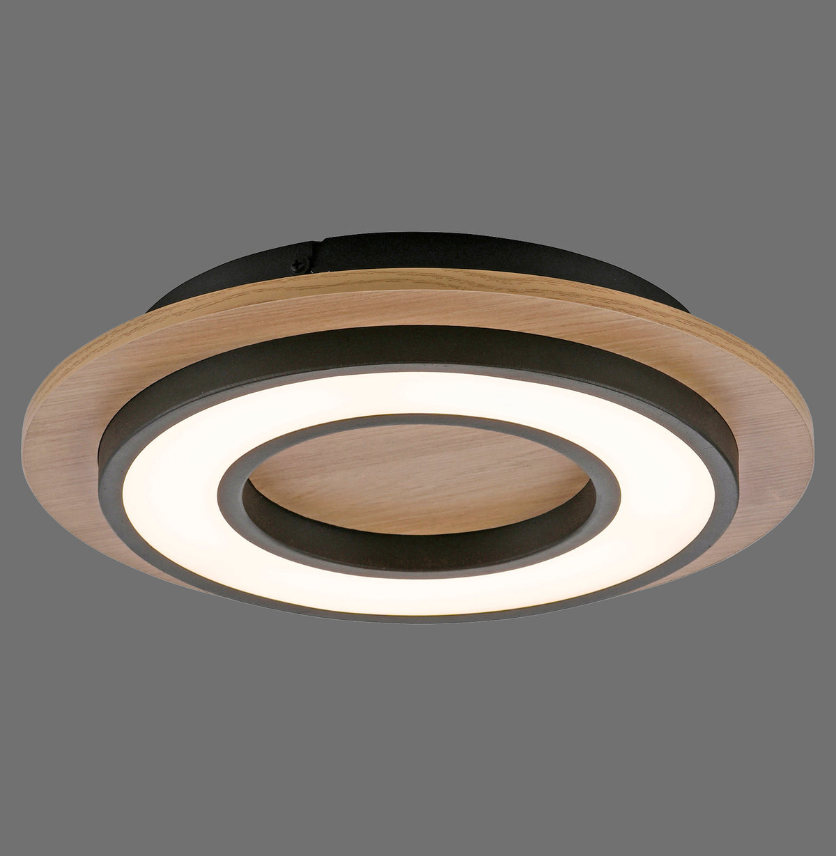 Plafonnier rond en bois clair et noir, anneau LED allumé, vue de trois quarts