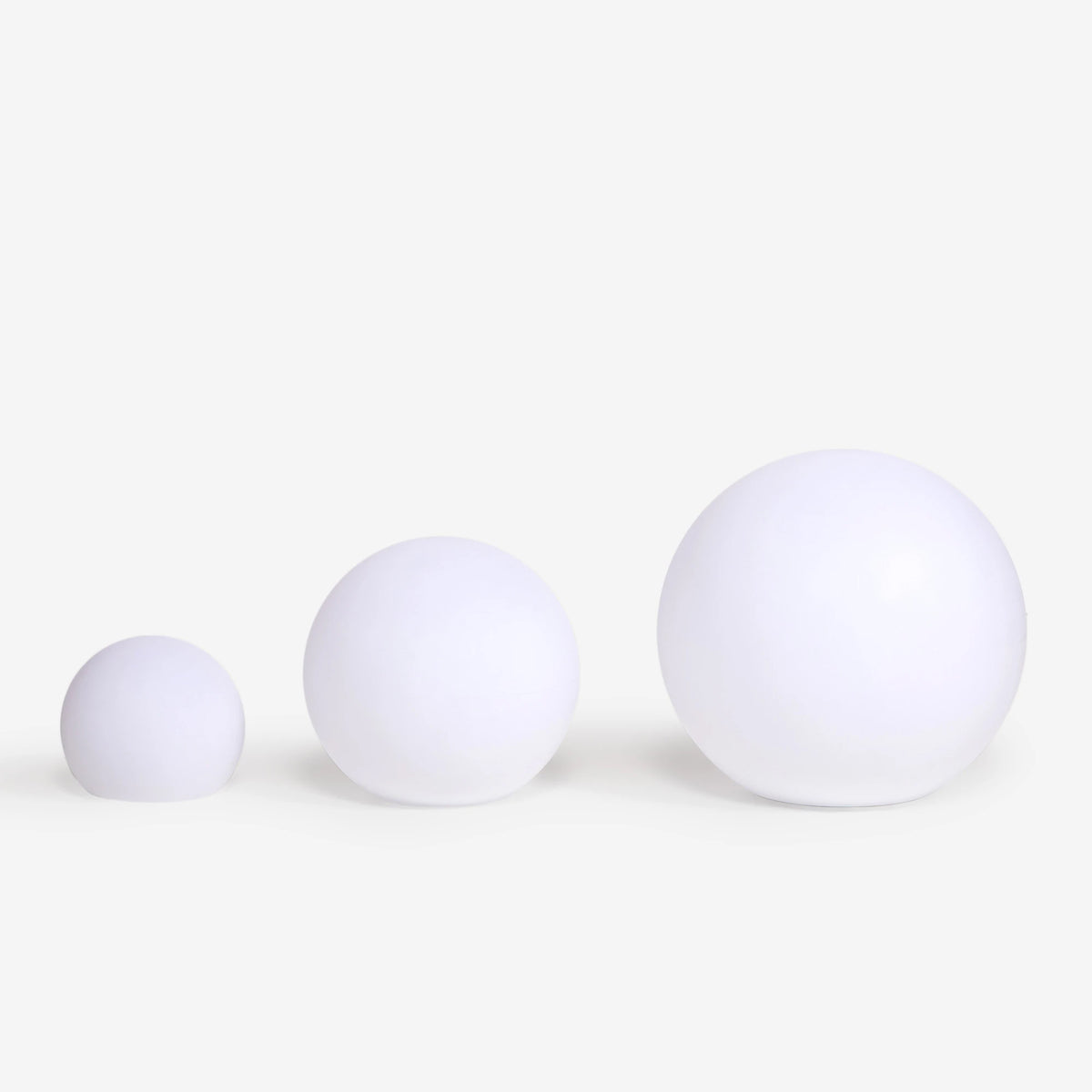 Trois boules blanches de tailles croissantes alignées pour comparer les formats