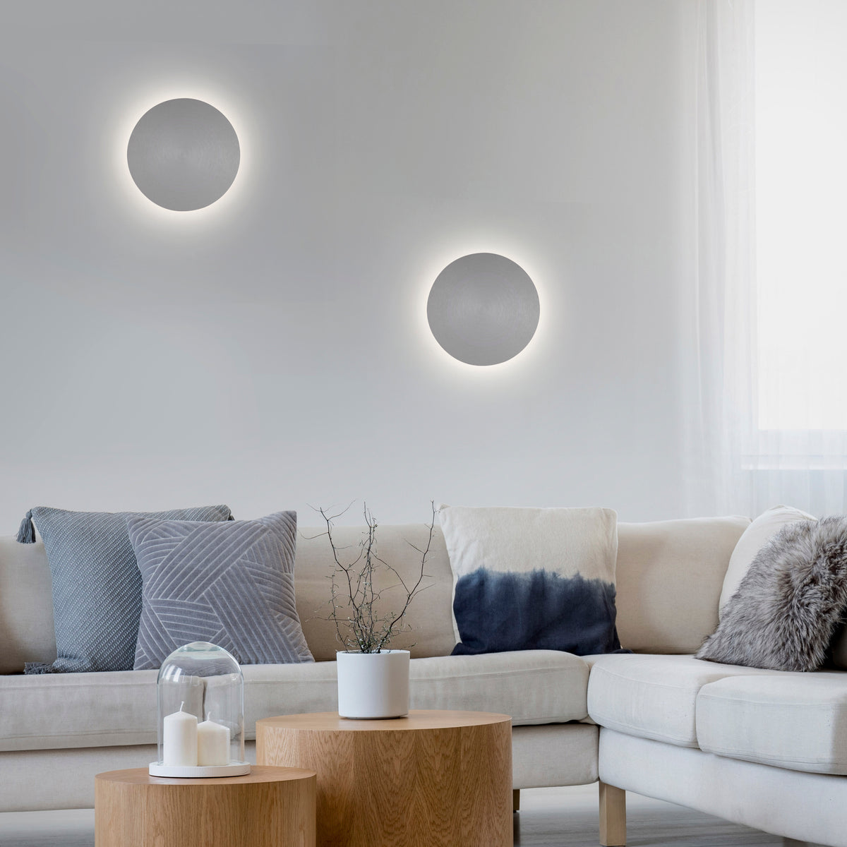 Mise en ambiance salon clair avec deux appliques rondes allumées au mur