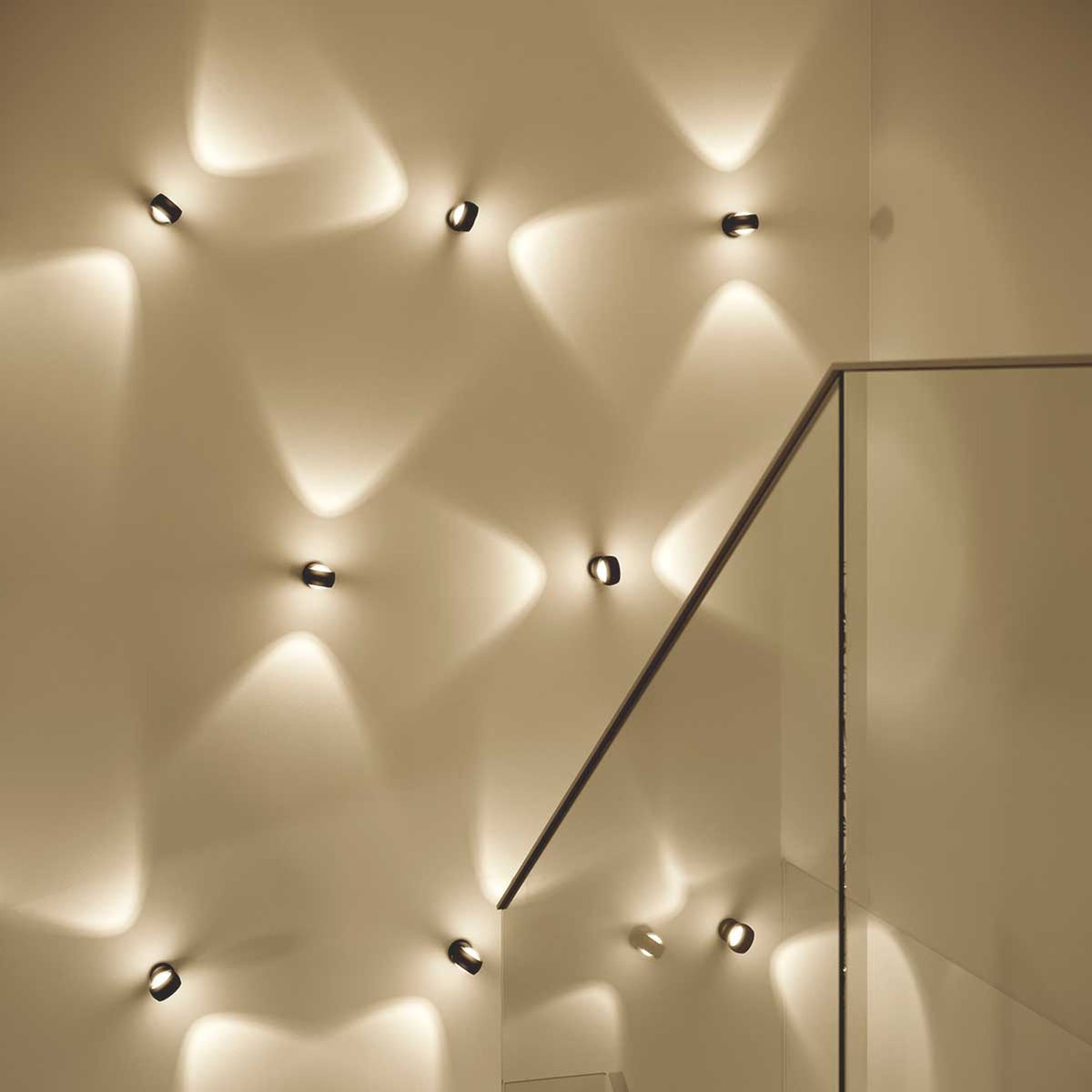 Vue de face d'appliques murales noires diffusant un halo lumineux haut et bas