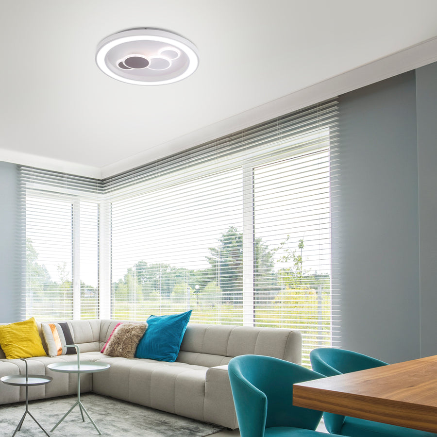 Plafonnier blanc installé au plafond d'un salon contemporain lumineux avec canapé et grandes fenêtres.
