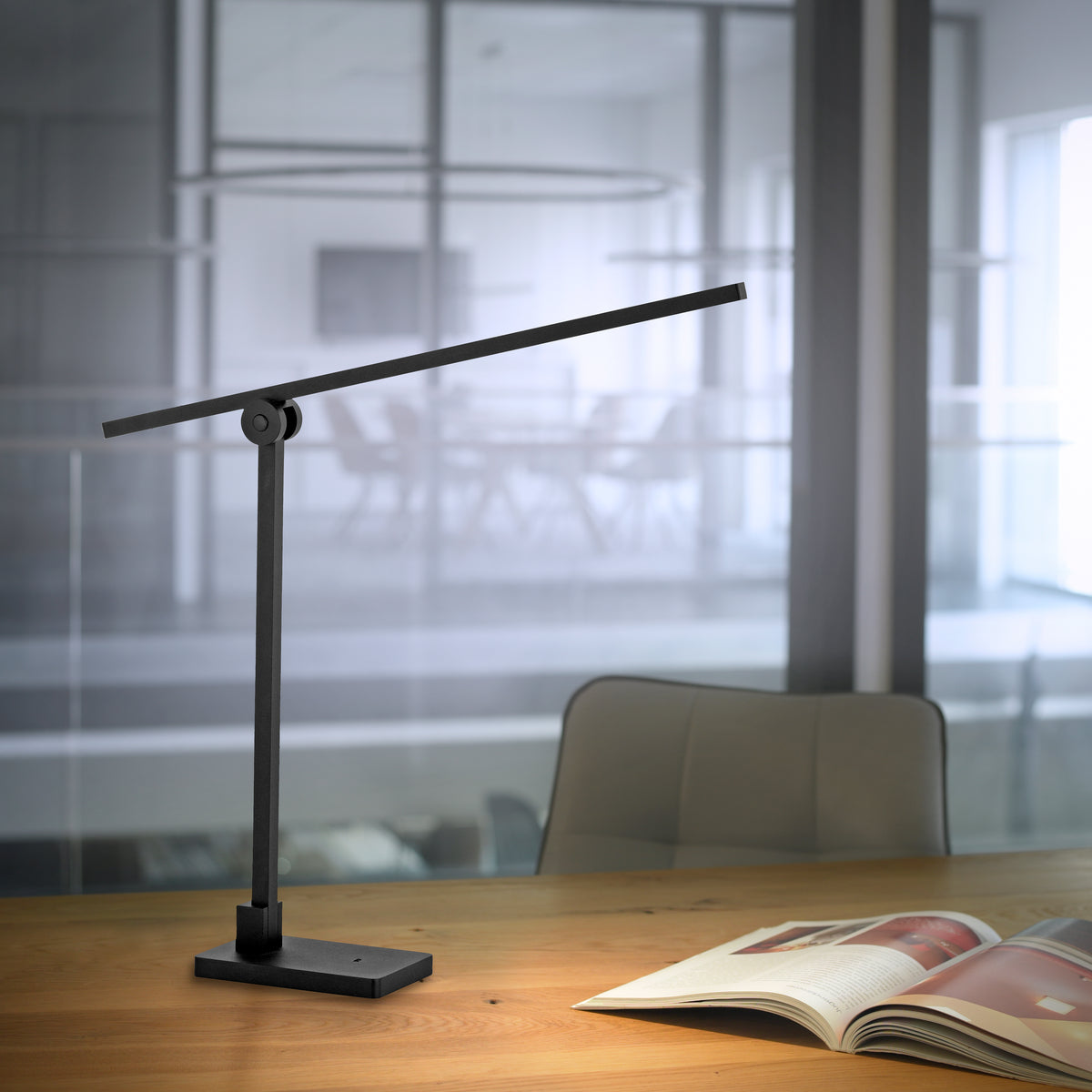 Mise en ambiance sur un bureau en bois, lampe allumée près d'un magazine ouvert