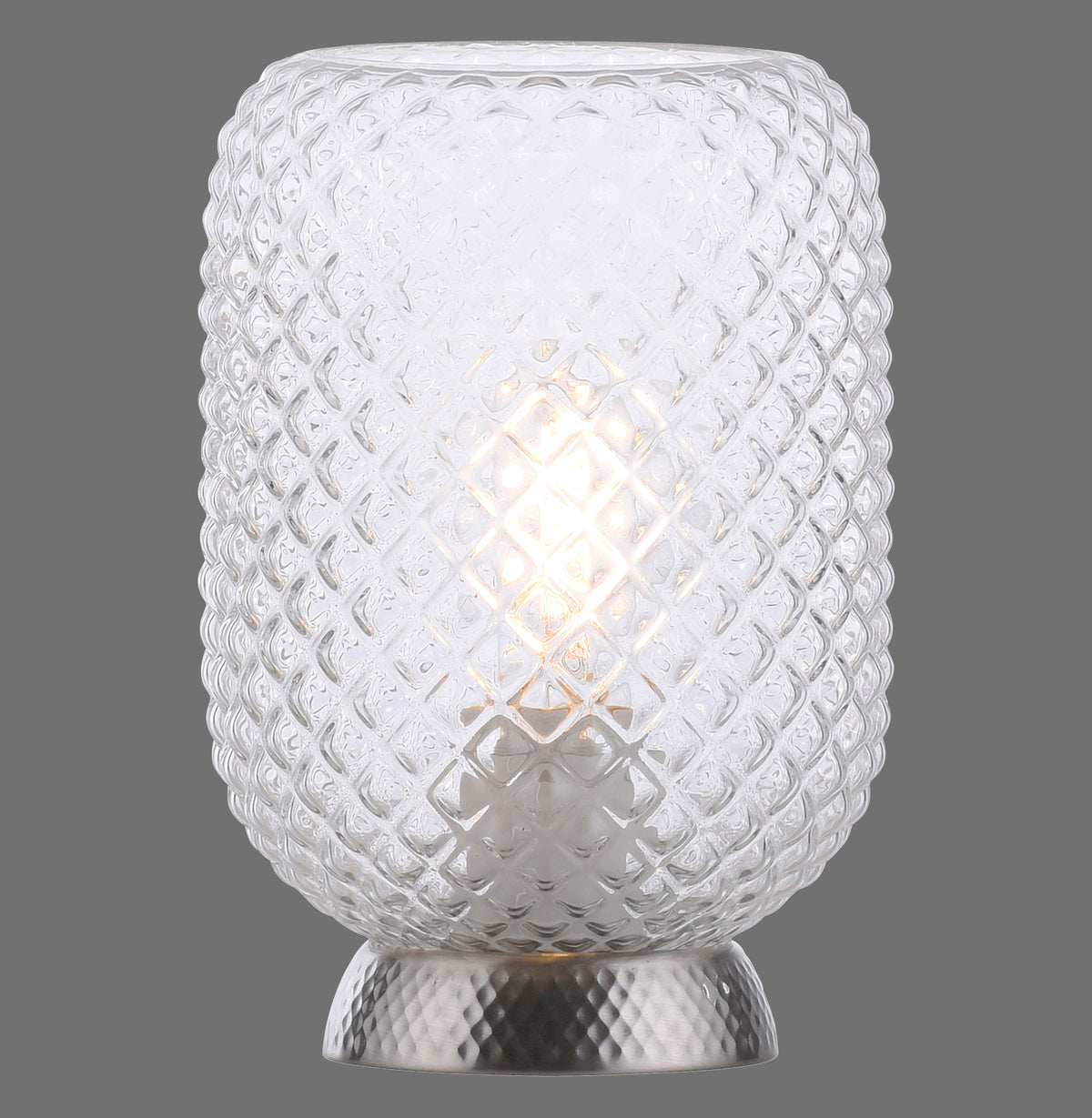 Lampe à poser en verre texturé, allumée, vue de face sur fond gris.