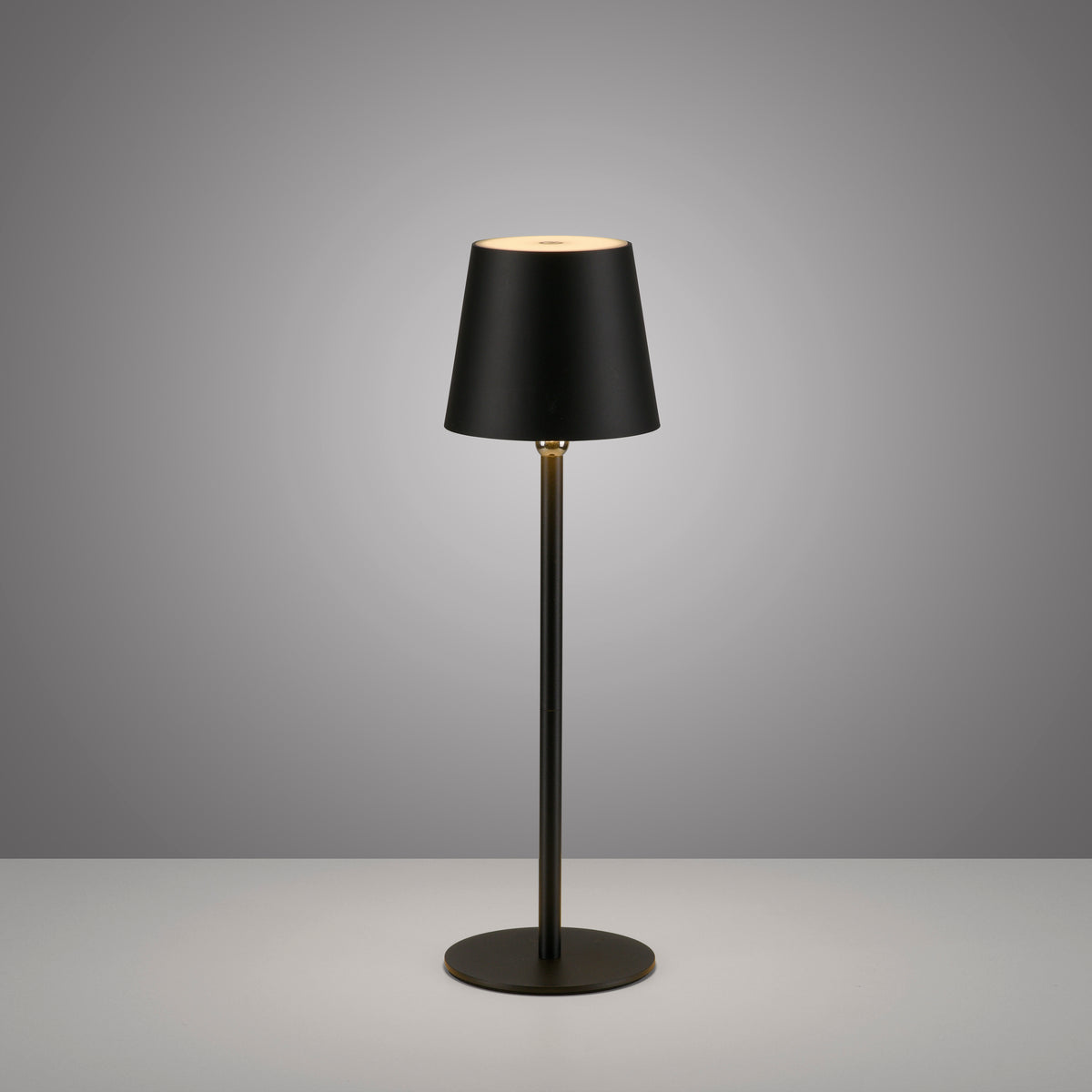 Lampe à poser noire droite sur fond gris, éclairage haut et bas visible.