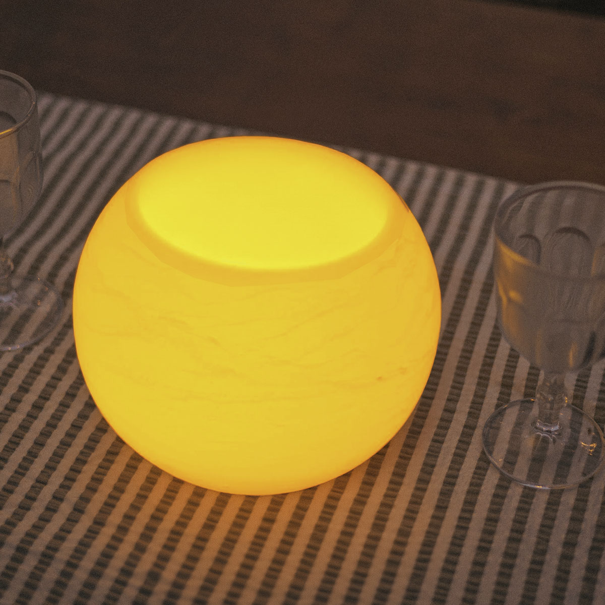 Gros plan du luminaire sphérique allumé posé sur nappe rayée