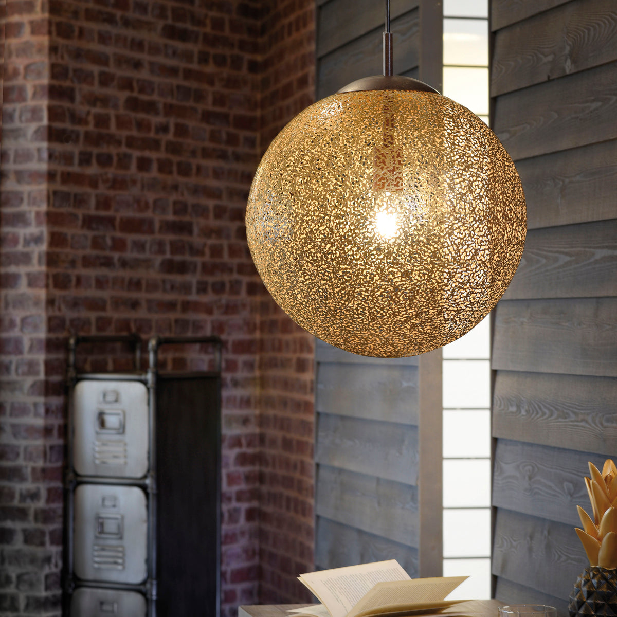 Mise en ambiance de la suspension dorée dans un intérieur industriel, près d'un mur en briques.