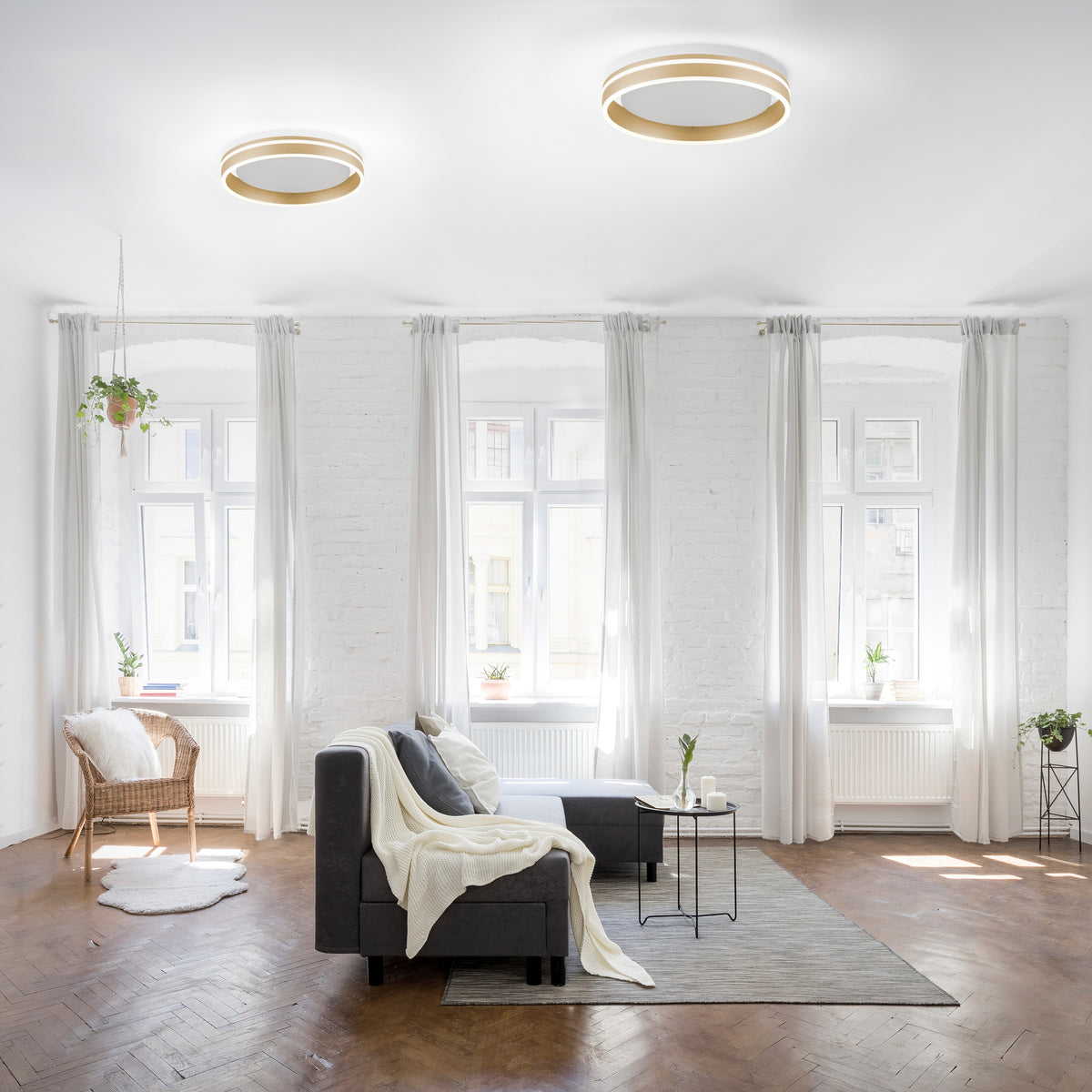 Mise en ambiance dans un salon clair, deux plafonniers ronds fixés au plafond.
