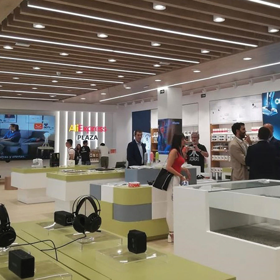Plafond d’un magasin avec spots ronds et bandeaux lumineux, ambiance commerciale.