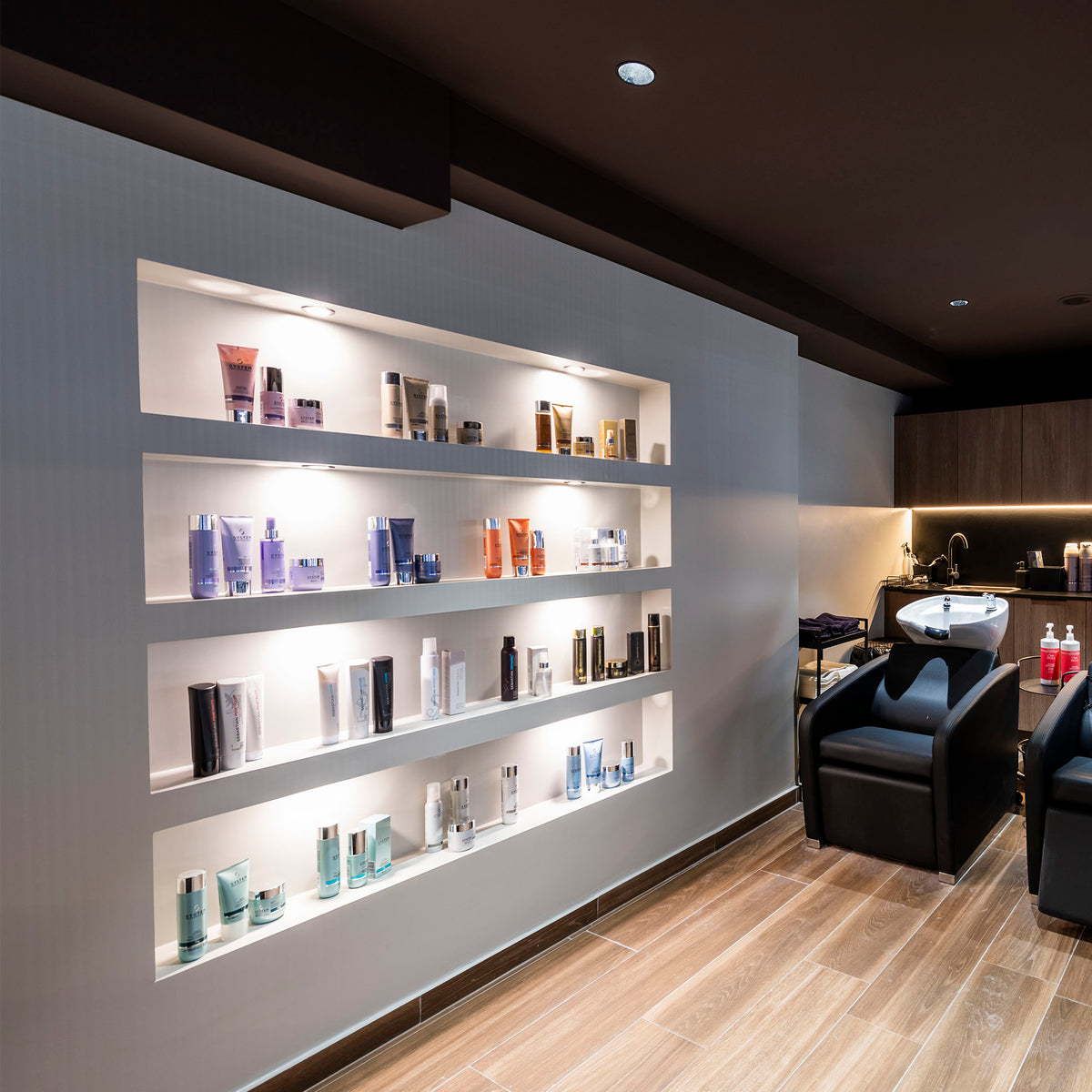 Mise en ambiance : spots encastrés éclairant des étagères de produits dans un salon.