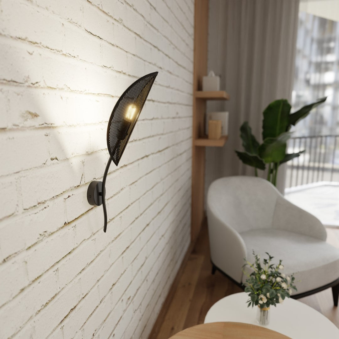 Luminaire mural feuille noire sur mur brique blanc, fauteuil et plante