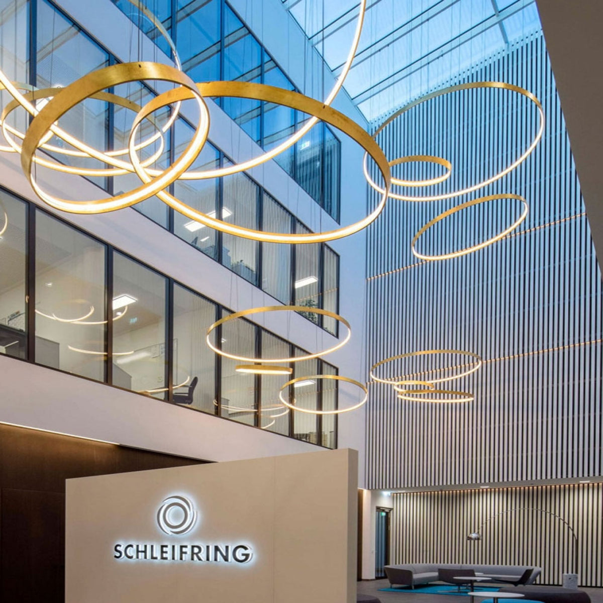 Ensemble d'anneaux lumineux suspendus dans un hall d'accueil avec logo mural