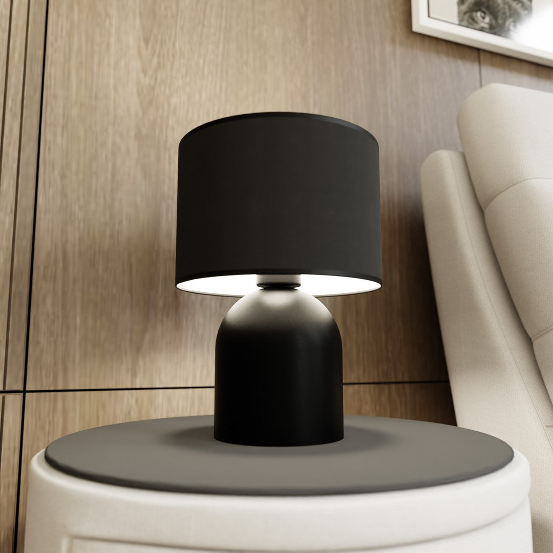 Mise en ambiance sur table ronde, lampe allumée sous l'abat-jour noir