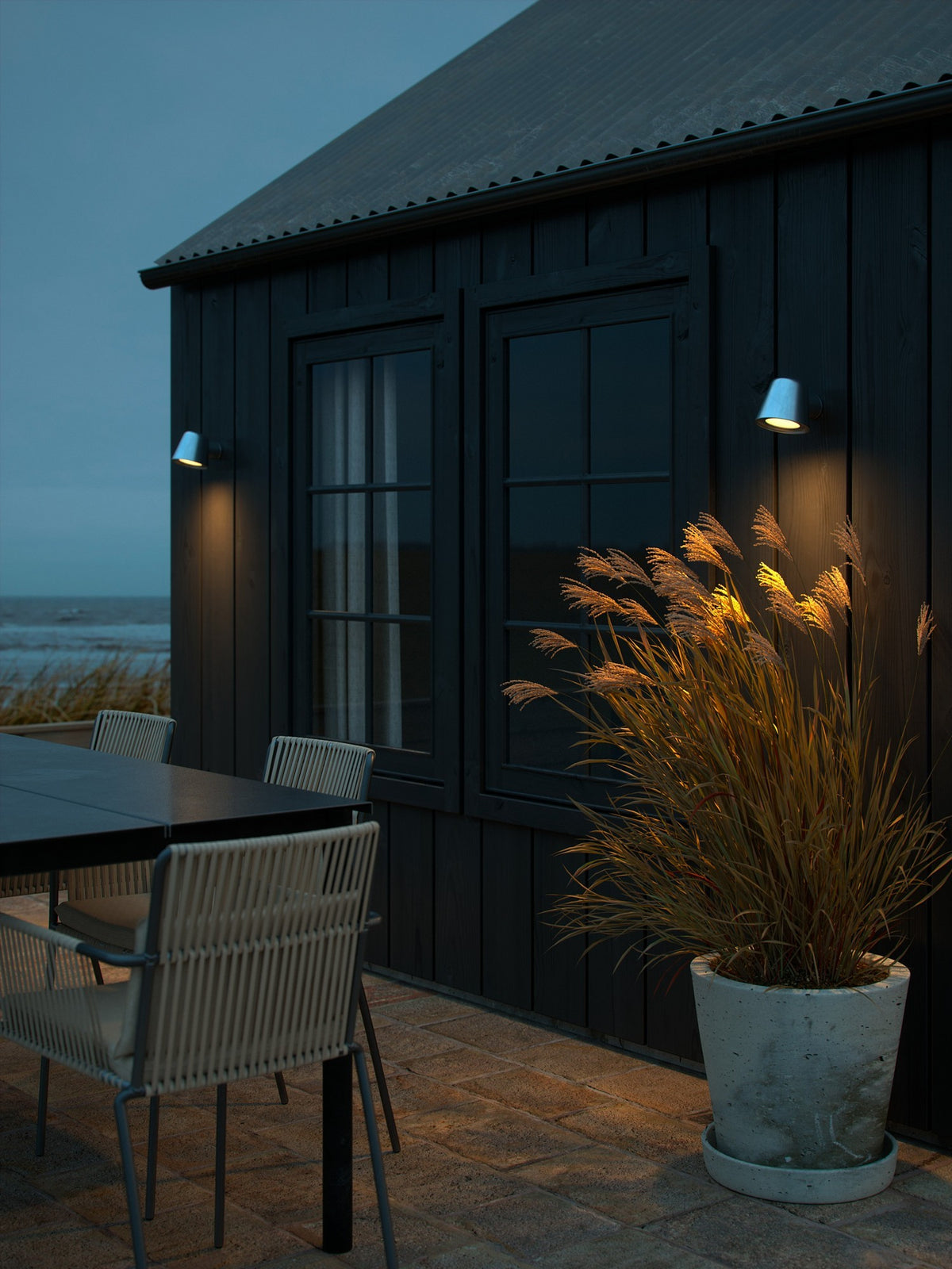 Mise en ambiance de nuit sur une façade en bois noir, éclairant une terrasse