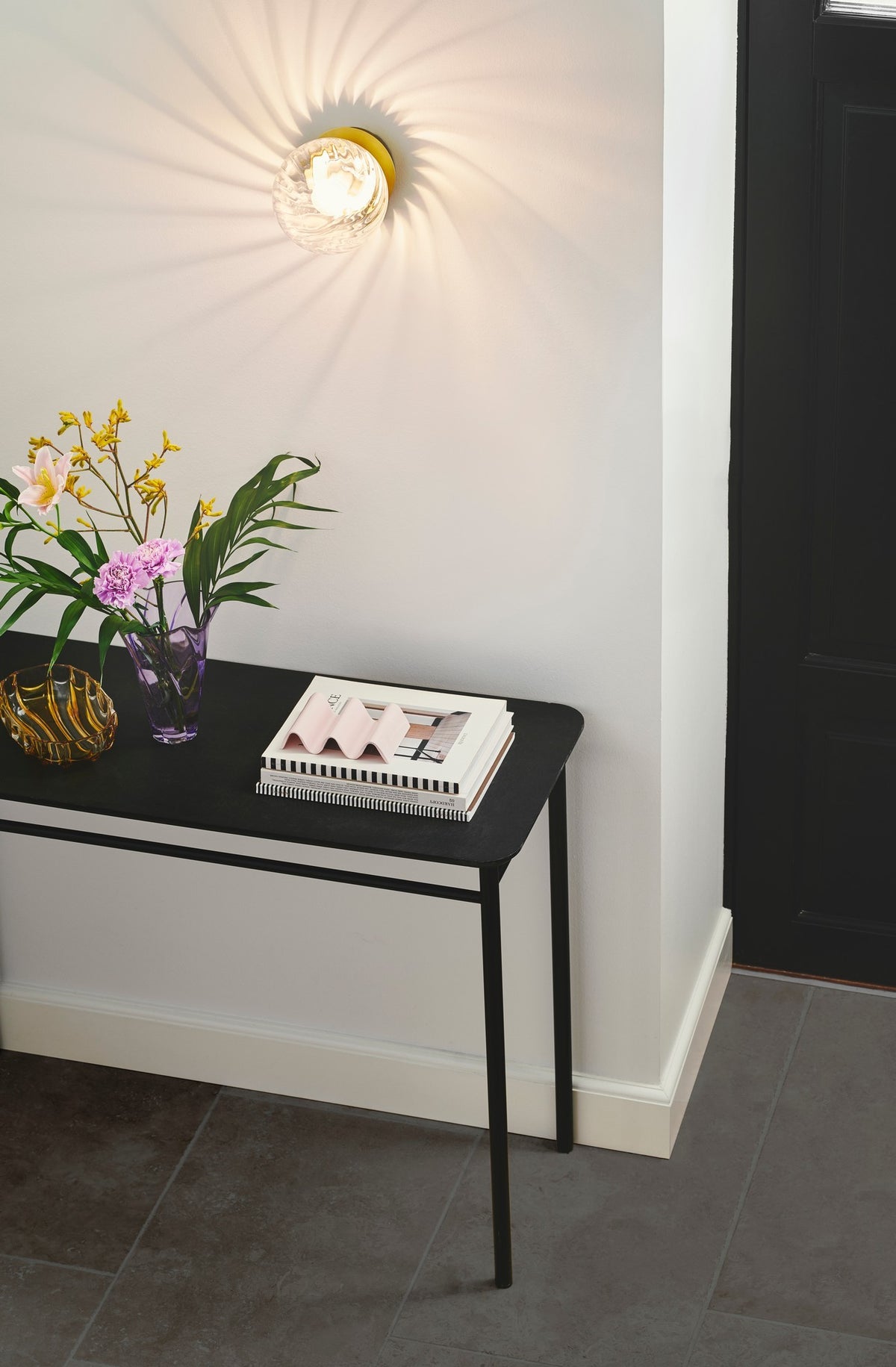 Mise en ambiance au-dessus d'une console noire dans une entrée claire
