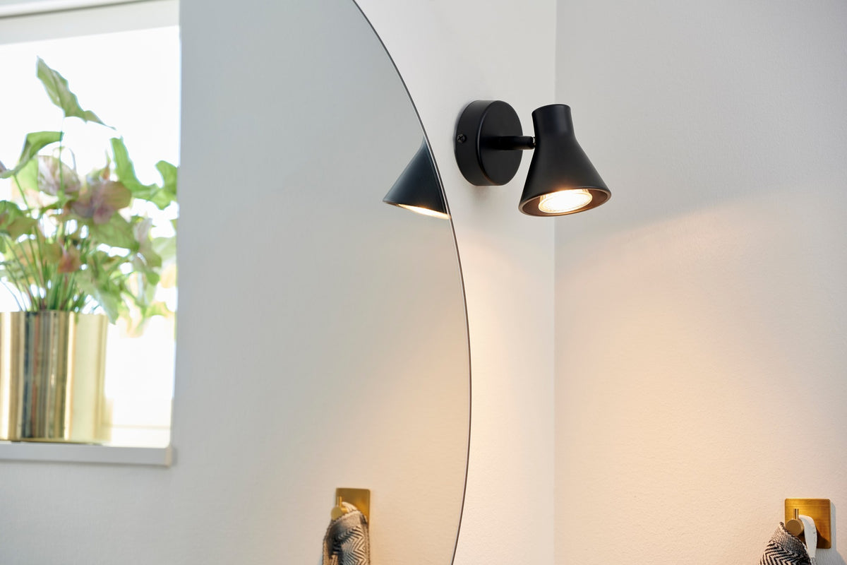 Mise en ambiance dans une salle de bain, applique noire près du miroir