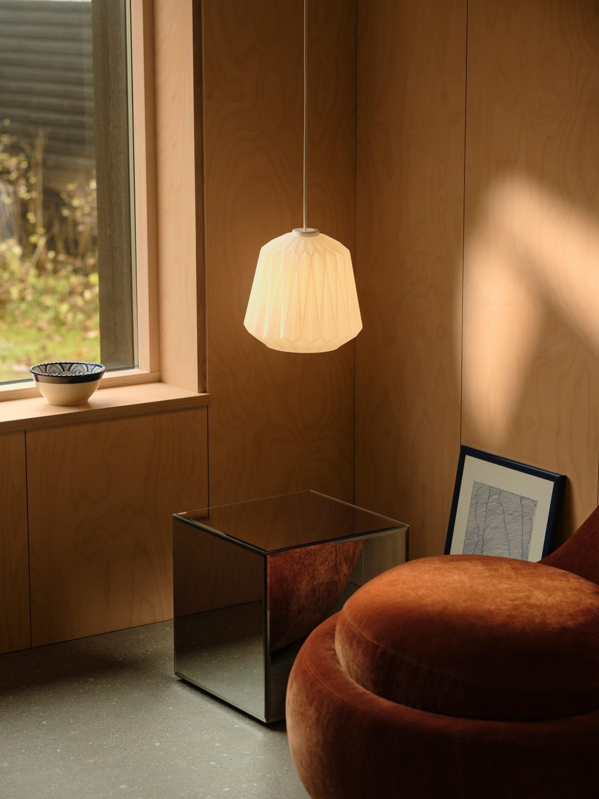 Mise en ambiance dans un intérieur bois, suspension allumée au-dessus d'un fauteuil