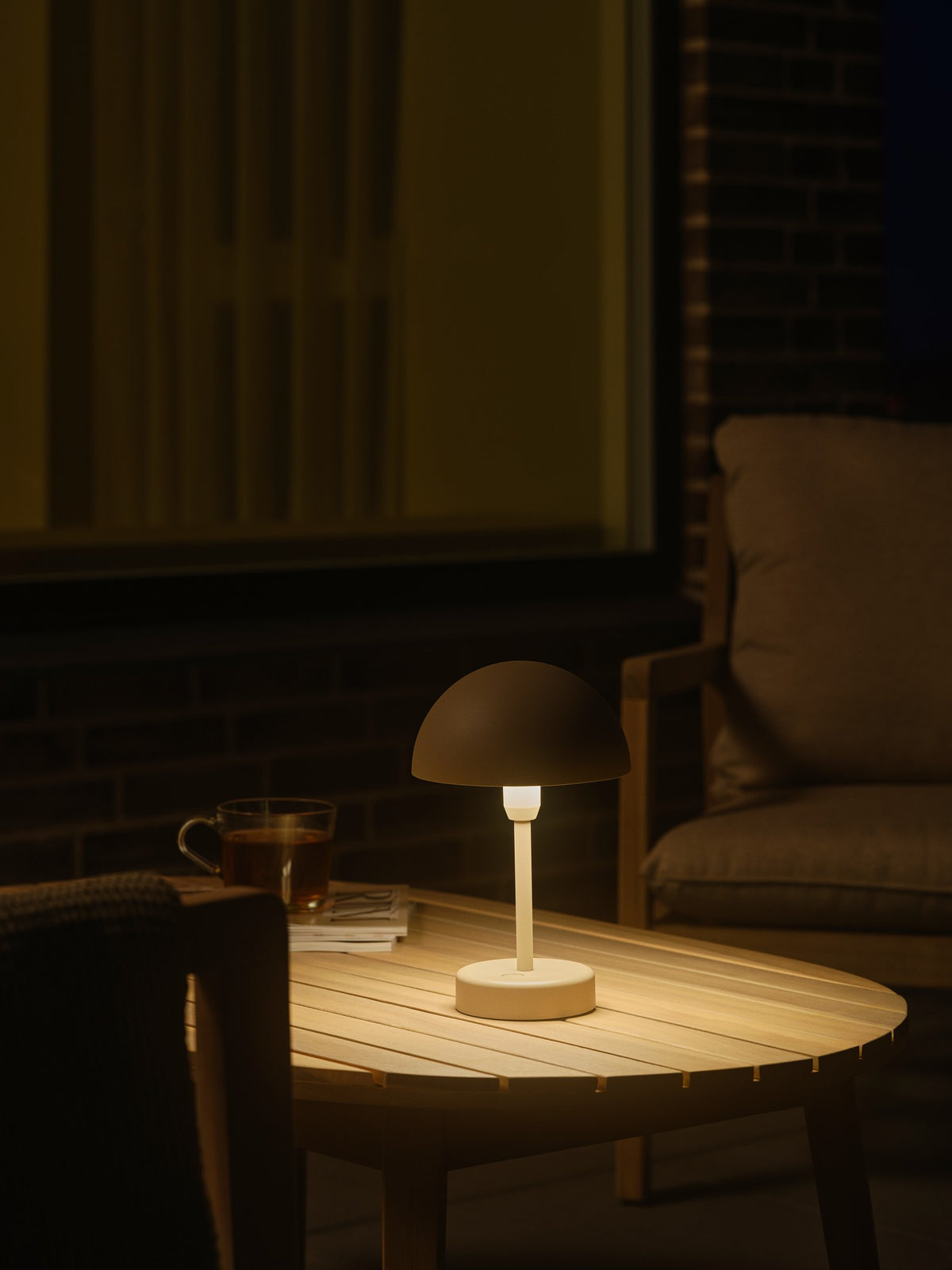 Mise en ambiance nocturne sur une table basse de terrasse avec boisson chaude.