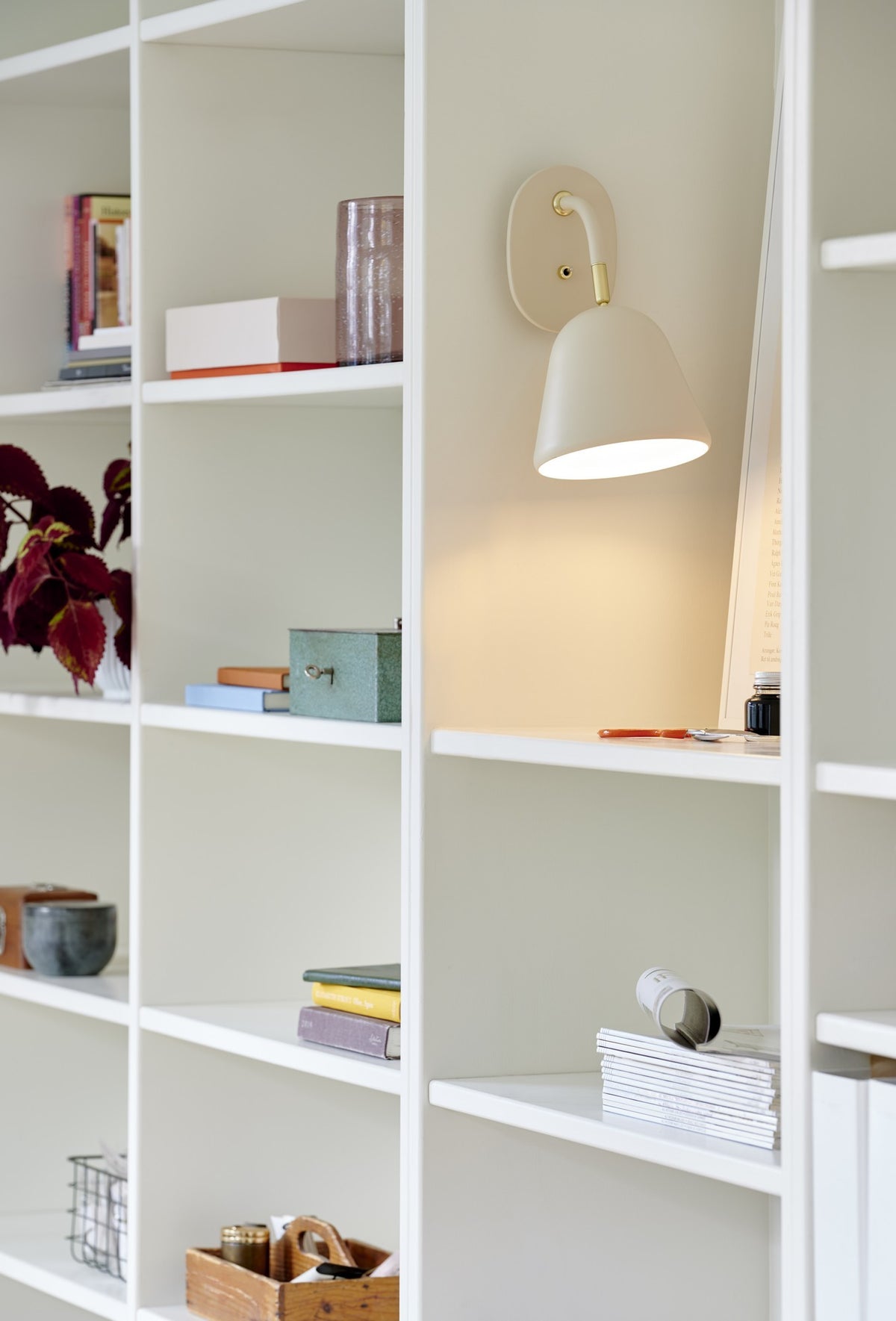 Mise en ambiance dans une bibliothèque blanche, lumière chaude sur les étagères