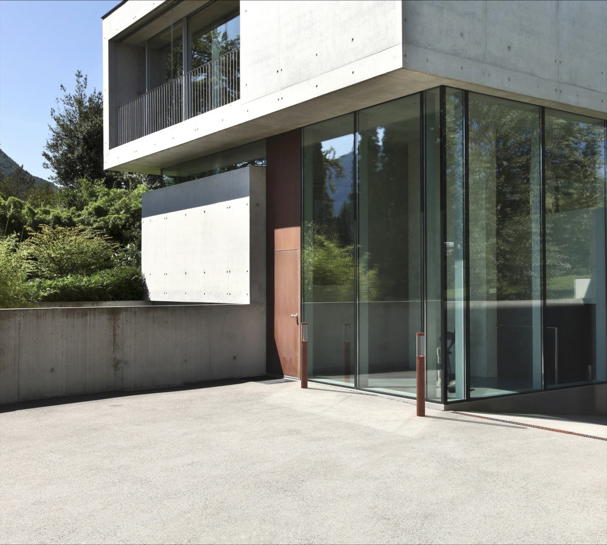 Deux bornes corten installées devant une façade contemporaine en béton et verre