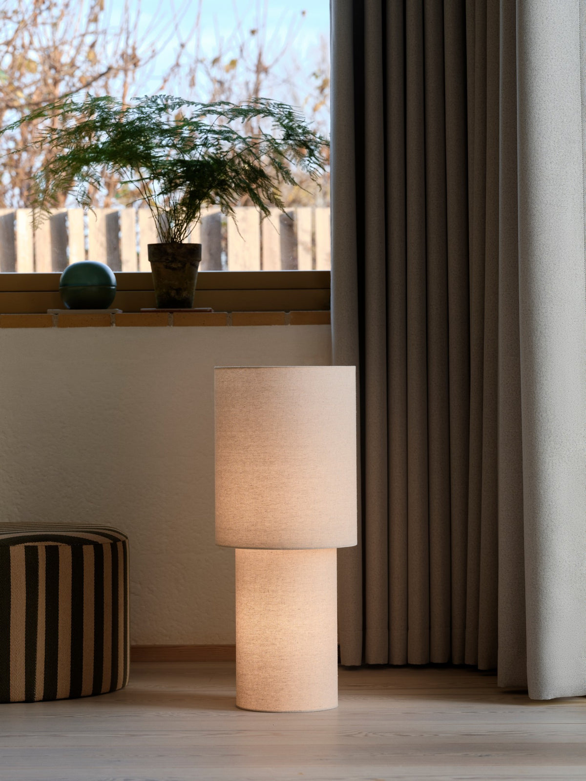 Mise en ambiance du lampadaire allumé près d'une fenêtre et de rideaux.