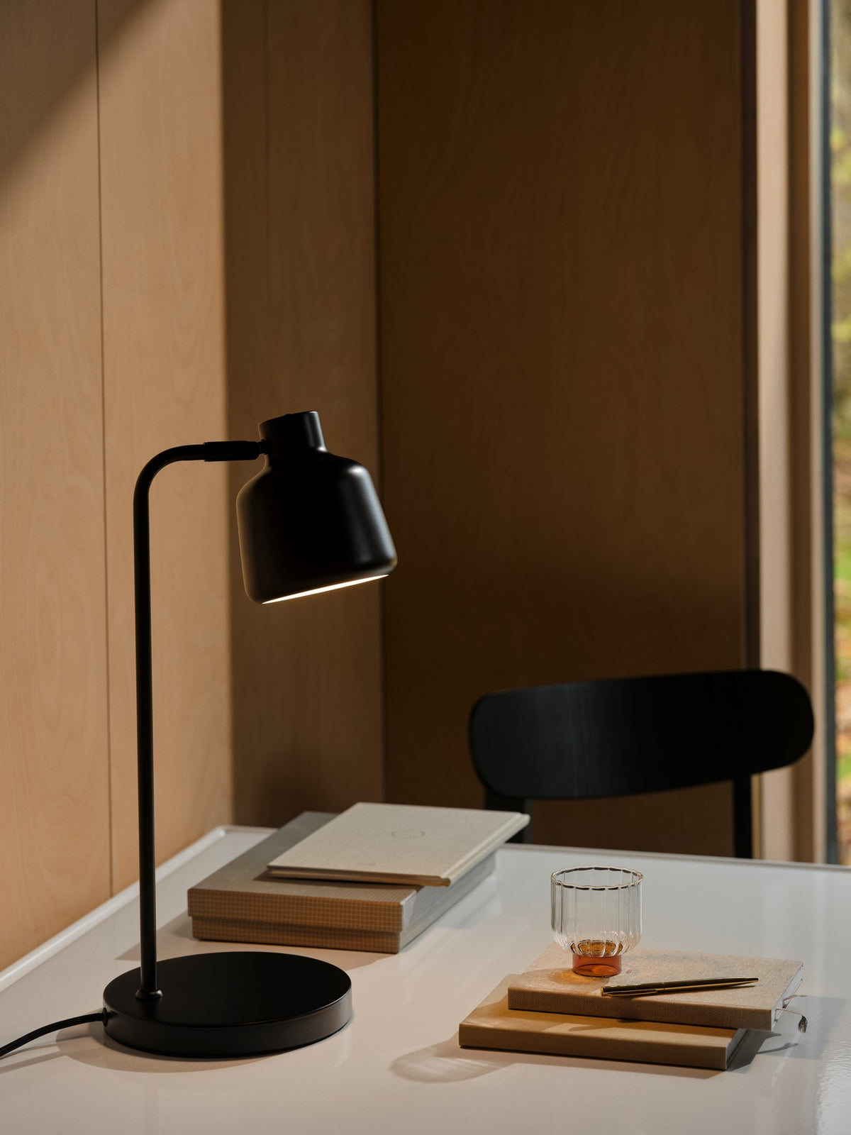 Mise en ambiance sur un bureau en bois avec livres et verre