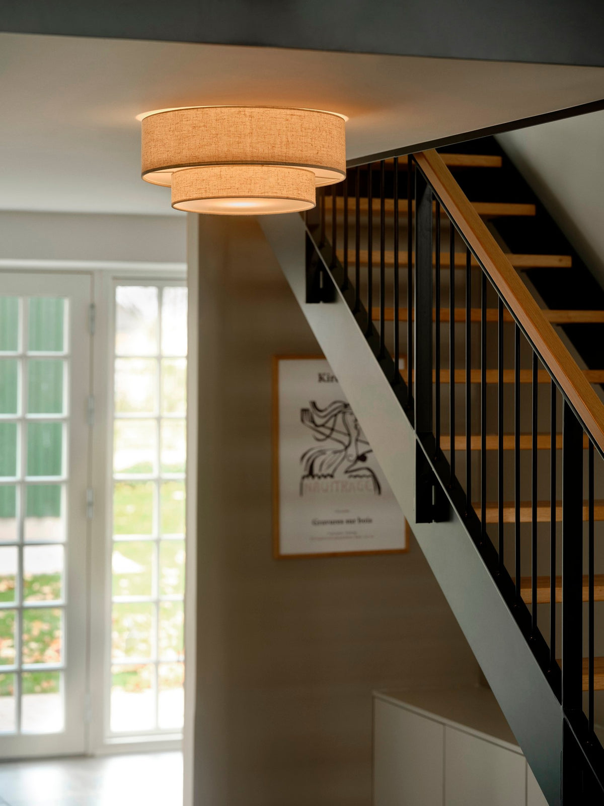 Mise en ambiance du plafonnier allumé au-dessus d'une cage d'escalier moderne.