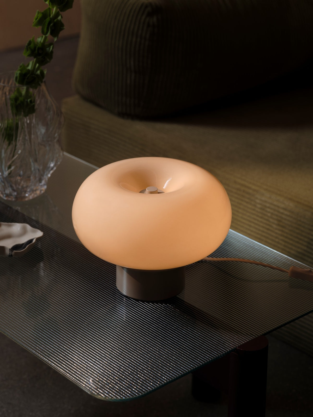 Mise en ambiance sur table en verre, lampe allumée près d'un vase
