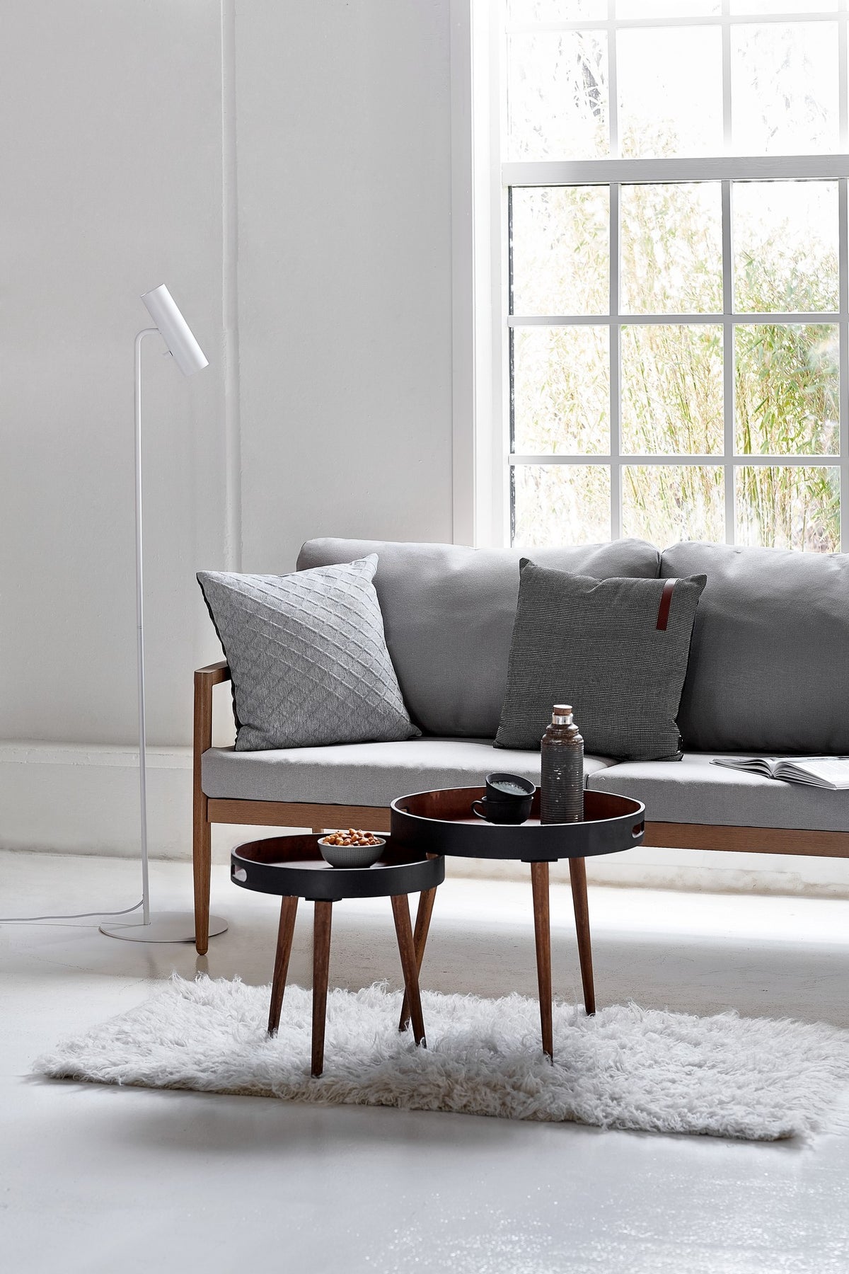Mise en ambiance : salon gris avec canapé, coussins et tables gigognes noires