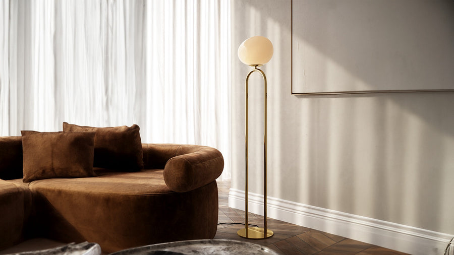 Lampadaire en situation dans un intérieur, devant mur blanc, canapé et parquet.