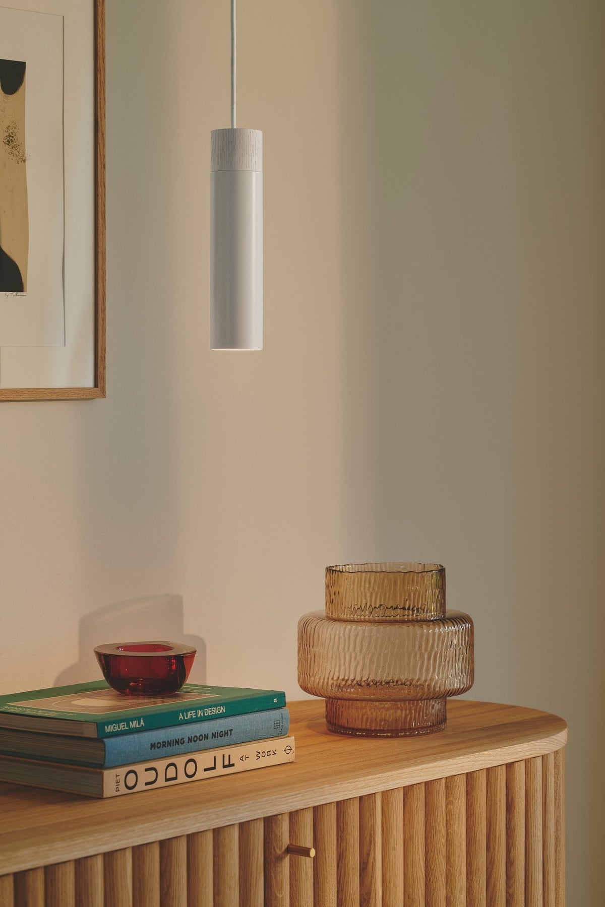 Mise en ambiance sur un meuble en bois clair avec vase et livres