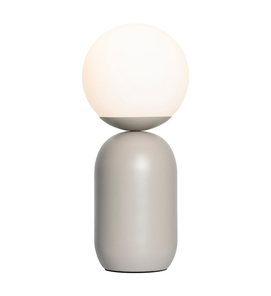 Lampe à poser de face, sphère en verre opalin éteinte sur socle cylindrique gris.