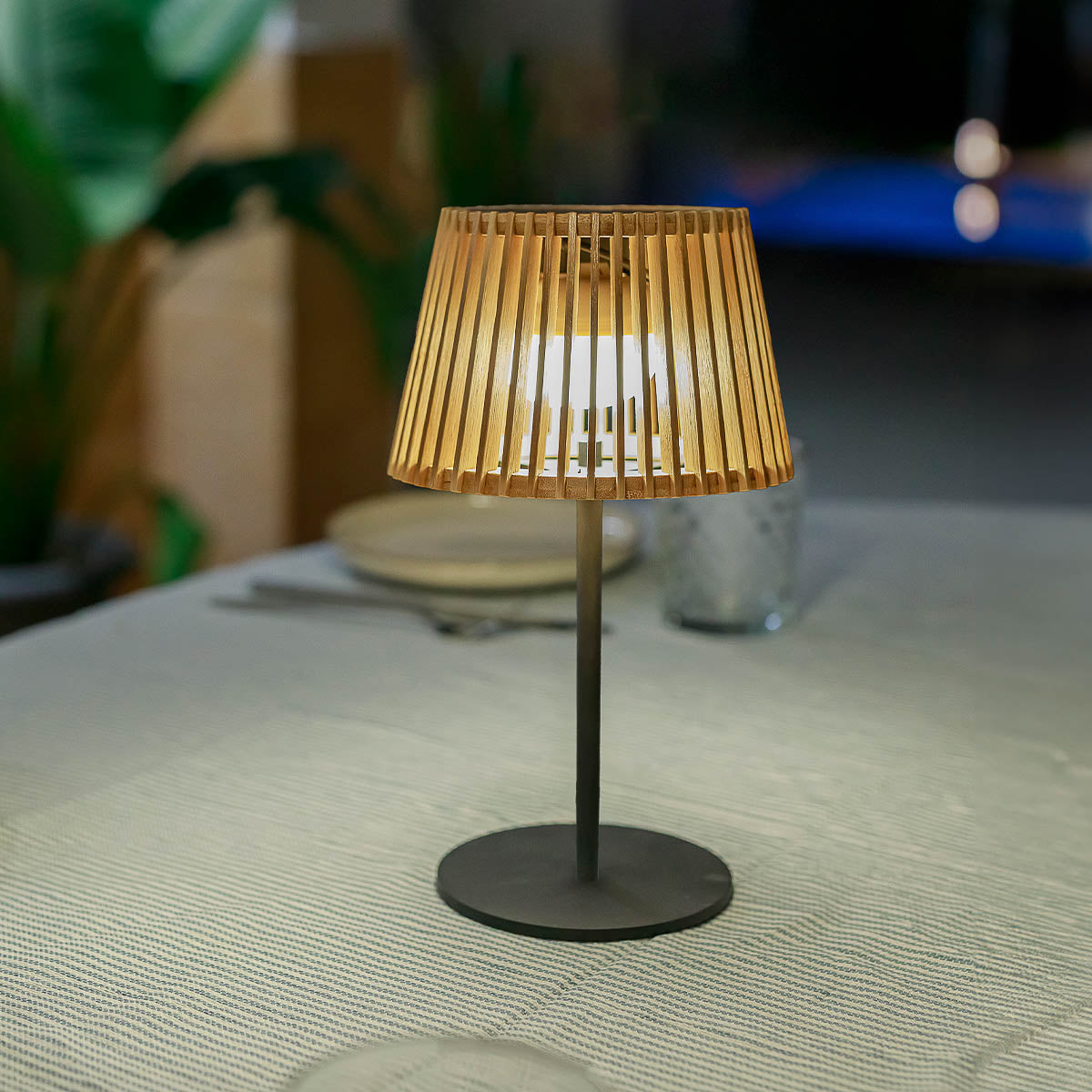 Gros plan du luminaire éclairé posé sur nappe claire, de trois quarts