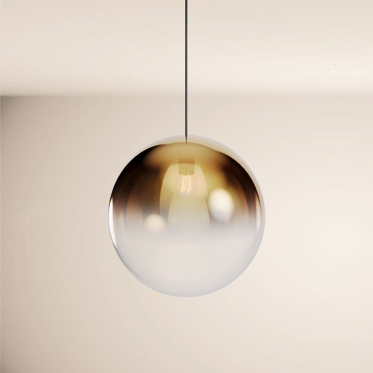 Vue rapprochée d'un globe en verre dégradé ambré et blanc, suspendu par un câble noir.