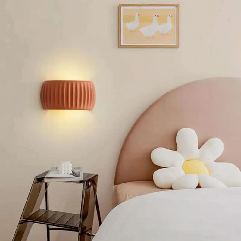 Applique murale terracotta rainurée au-dessus d'une table de chevet, près d'un lit.