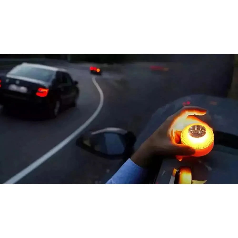 Lampe allumée tenue à la main près d'une voiture, de nuit sur la route.