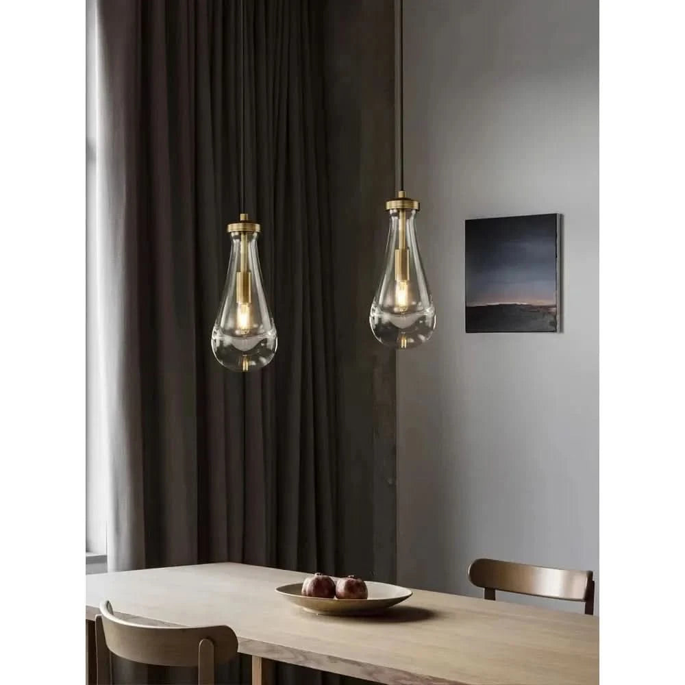 Deux suspensions en verre transparent suspendues au-dessus d'une table en bois, décor de salle à manger.