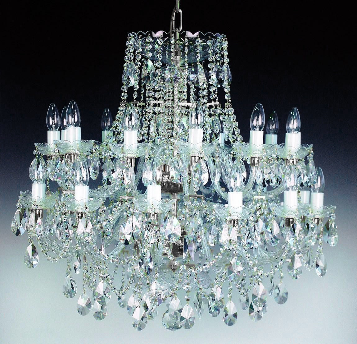 Vue frontale du lustre sur dégradé sombre, cristaux taillés et bras en verre translucide.