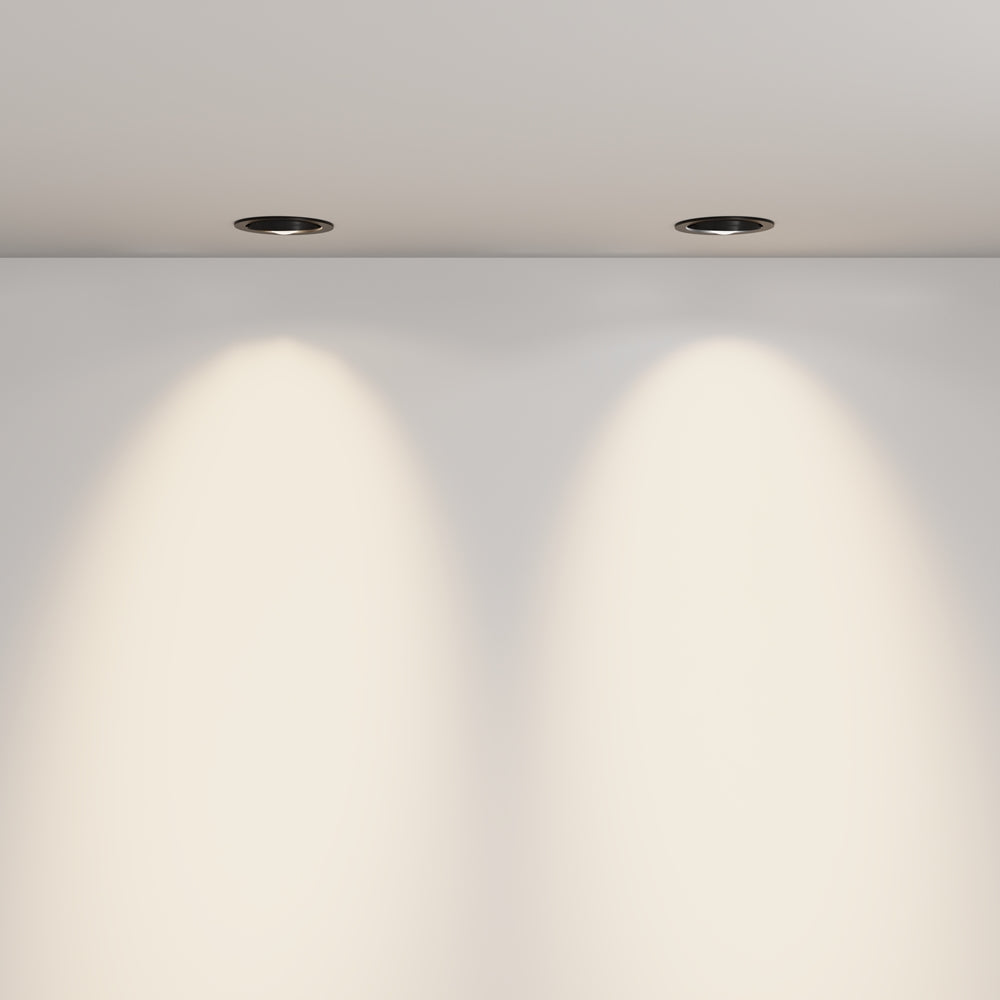 Deux spots encastrés au plafond projetant des cônes de lumière sur un mur