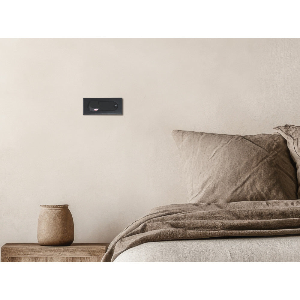 Mise en ambiance murale au-dessus d'un lit avec applique encastrée noire allumée.