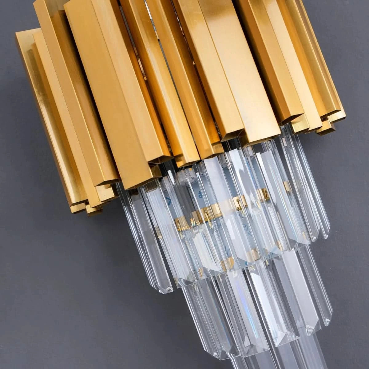 Détail rapproché des tubes dorés et des tiges de cristal du luminaire