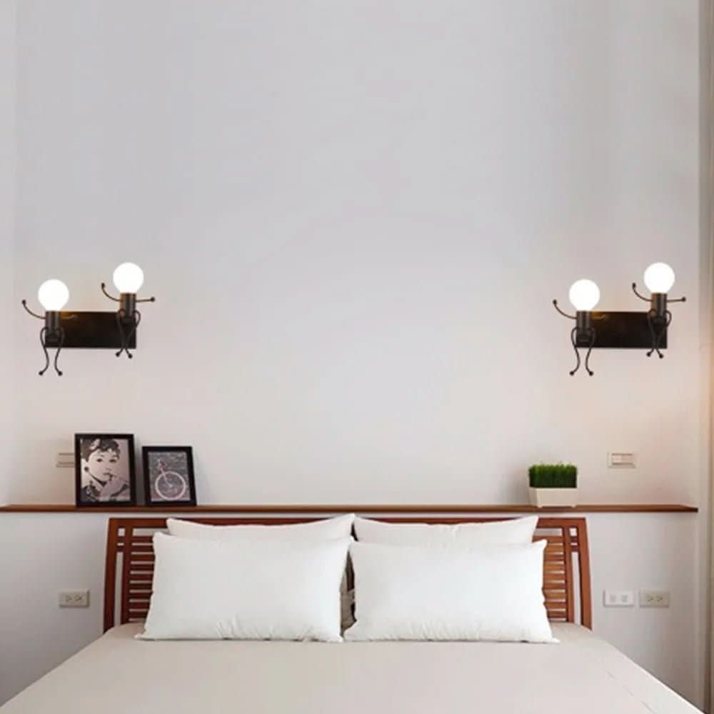 Chambre avec deux appliques noires fixées au mur au-dessus d'une tête de lit en bois.