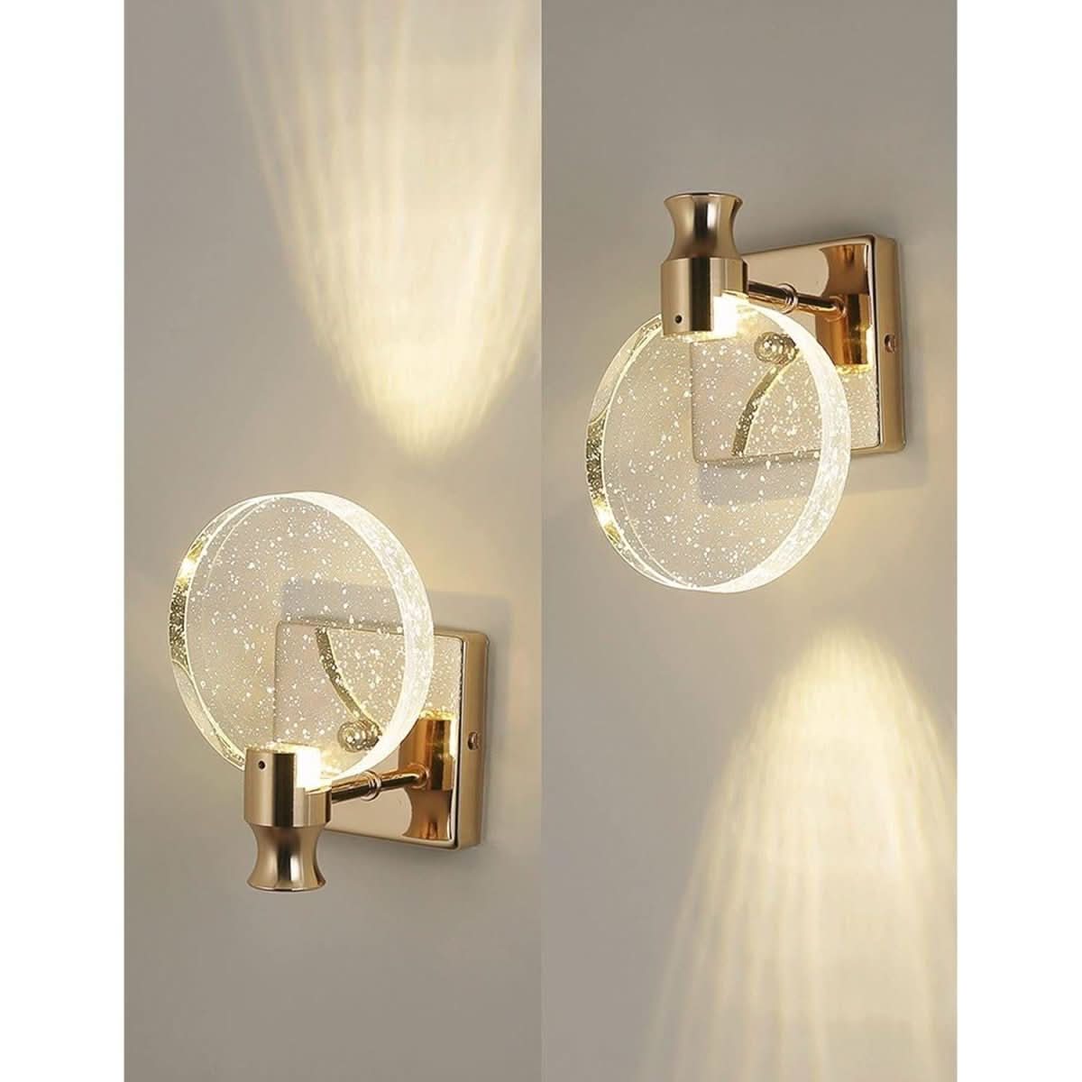 Deux appliques murales dorées vues de trois quarts, ombres lumineuses sur le mur